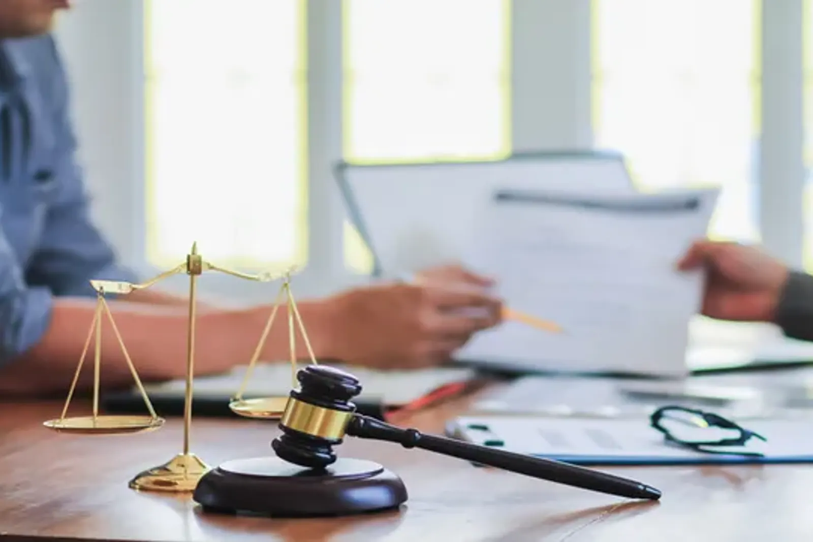 Balanza y mazo judicial sobre un escritorio con documentos en revisión