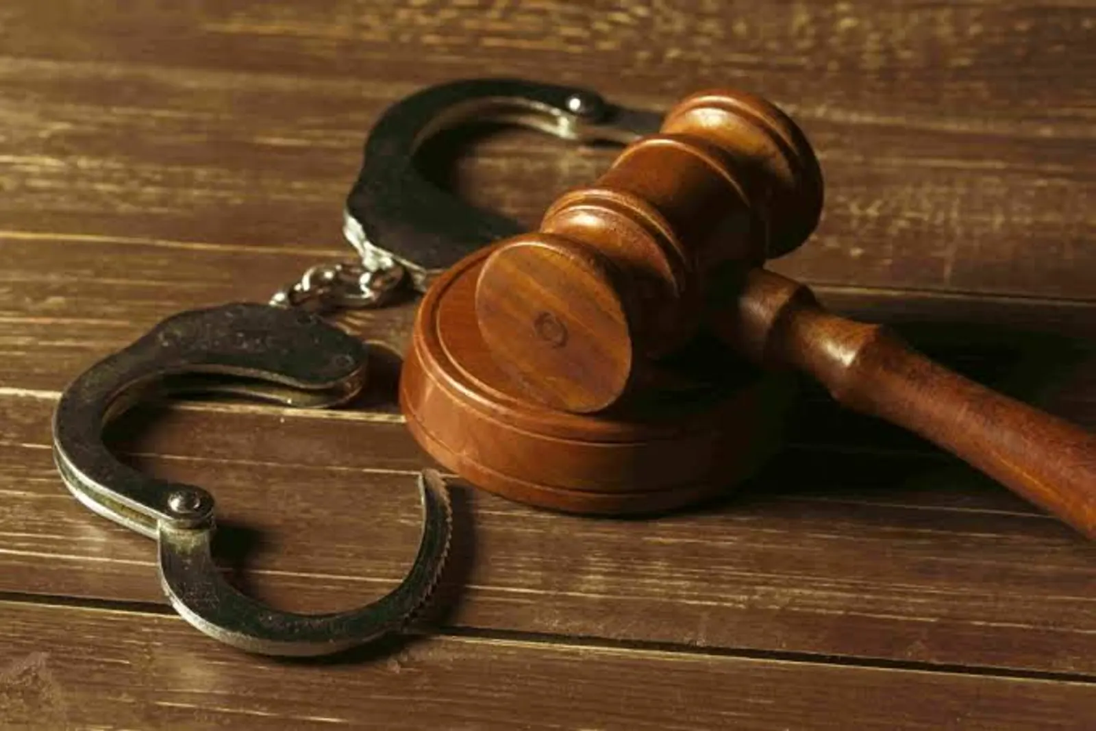 Unas esposas y un mazo judicial sobre una mesa de madera