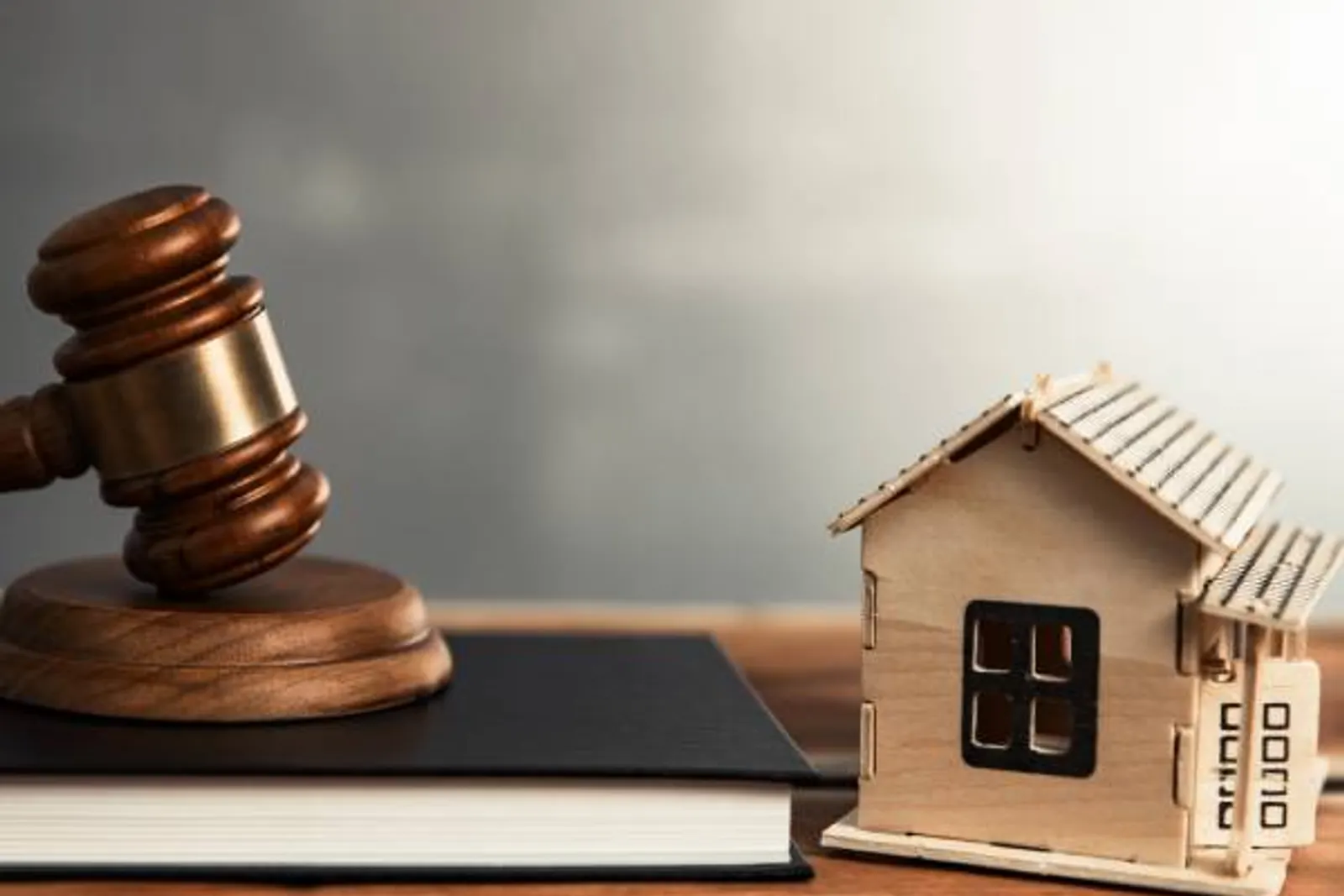 Mazo judicial junto a la maqueta de madera de una casa